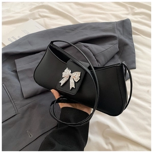 Détail d'un sac baguette en cuir PU noir brillant avec une boucle papillon en métal argenté