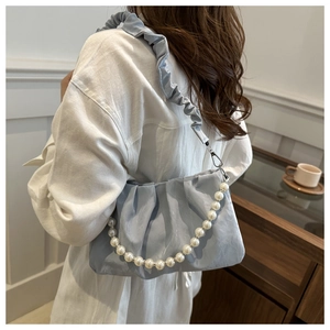 Close-up of light blue cloud bag with delicate pleats and white pearl chain decoration