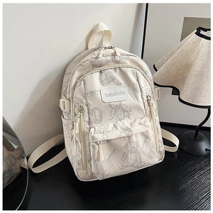 Detail of a cream canvas backpack with grey bear print on a black wooden desk