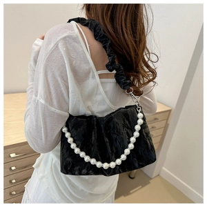 Detail view of black pleated cloud bag with white pearl chain and ruffled fabric strap