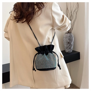 Detail of a black drawstring bucket bag with blue and silver rhinestones on a beige blazer