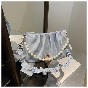 Detail of light blue pleated handbag with pearl handle and ruffled shoulder strap close-up