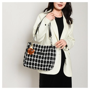 Detail of checkered tweed tote bag with metal chain strap and cute bear plush charm