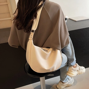 Minimalist beige nylon crescent crossbody bag with adjustable wide shoulder strap and zipper