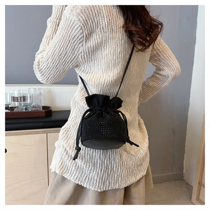 Detail of a black rhinestone bucket bag with drawstring closure and slim shoulder strap