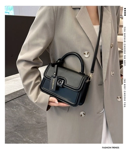 Side view of black leather crossbody bag on grey blazer showing strap and fashion tag