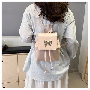 Detailed close-up of the pink leather backpack with a metal butterfly clasp and tassels