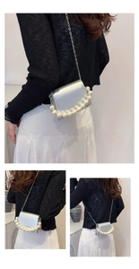 Detail of silver metallic crossbody bag featuring pearl handle and fine metal chain strap