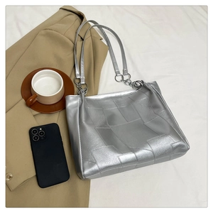 Detail showing metallic silver tote bag with large quilted patterns and silver chain strap