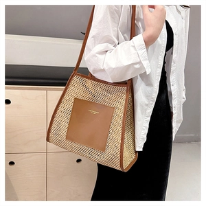 Detail of hollow woven straw tote bag with brown leather pocket and shoulder strap