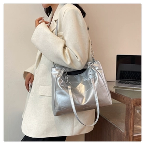 Detailed shot of silver geometric tote bag with chain strap on model for urban commute