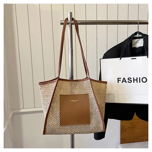 Close-up of woven straw tote bag with brown leather handles and a fashion brand logo patch