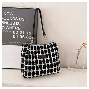 Detail of black and white tweed tote bag with silver chain strap in home setting