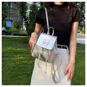 Outdoor shot of a silver metallic mini backpack featuring a bow buckle and drawstring