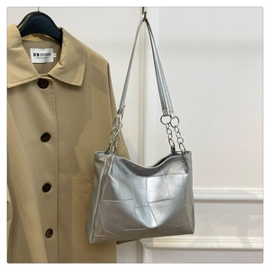 Detail of silver metallic patchwork tote bag with geometric design and chain strap