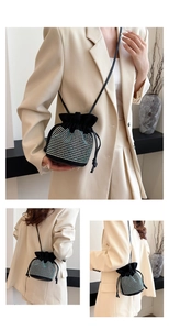 Detail of black drawstring bucket bag with shimmering rhinestones and thin shoulder strap