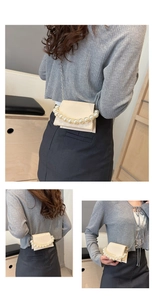Detail view of a cream mini bag featuring elegant pearl handle and metal chain strap