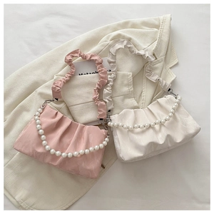 Detail of pink and beige pleated bags with pearl handles and ruched straps on a blazer
