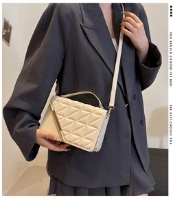 Close-up of cream quilted crossbody bag with geometric triangle stitching and thin strap