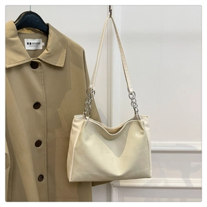 Close-up of beige PU leather shoulder bag with irregular square stitching and silver ring chain