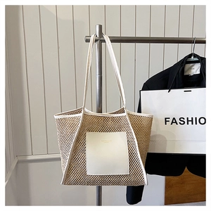 Detail view of woven straw tote bag featuring white leather pocket and hollow pattern