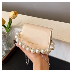 Detail of cream white mini crossbody bag with large pearl handle and silver chain strap