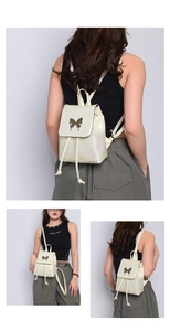Detail of cream white mini backpack featuring metal butterfly buckle and drawstring closure