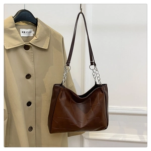 Detail of vintage brown leather tote bag with geometric stitching and silver chain strap