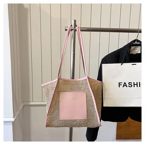 Detail of the woven straw texture and pink leather trim on this large summer tote bag
