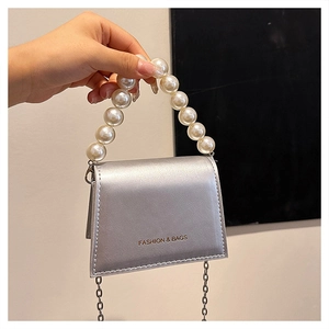 Detail of silver metallic mini bag featuring large pearl handle and metal chain strap
