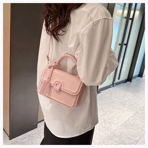 Detail of light pink crossbody square bag featuring a FASHION tag and top handle