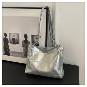 Detail of silver metallic tote bag with geometric stitching and metal ring strap chain