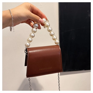 Detail of brown mini crossbody bag with large pearl handle and gold chain strap