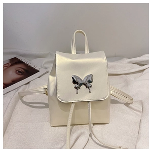 Detailed view of cream mini backpack with silver metal butterfly and glossy finish
