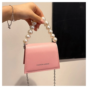 Detail of pink mini handbag with oversized pearl handle and silver chain strap
