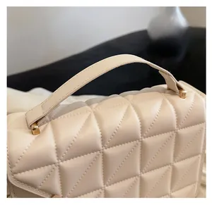 Close-up of cream quilted leather handbag with gold metal hardware and comfortable handle