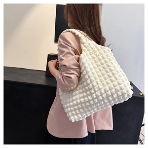 Detailed texture view of a white bubble quilted large tote bag worn with a pink blazer