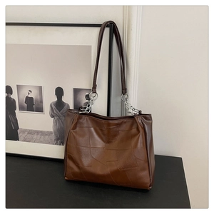 Detail of vintage brown tote bag showing geometric leather stitching and silver chain strap