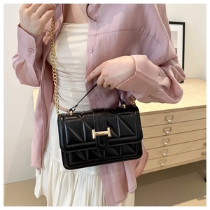 Close-up of black quilted shoulder bag with gold chain strap and metal clasp detail