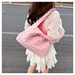 Detailed bubble texture of pink pleated shoulder bag worn by model in street setting