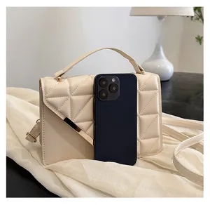 Close-up of beige quilted crossbody bag showing size comparison with a smartphone