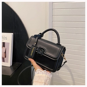 Detail shot of black leather handbag with fashion tag and golden metal hardware