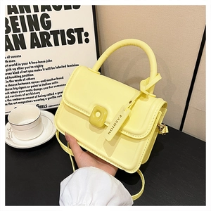 Detail of light yellow crossbody square bag with top handle and fashion buckle