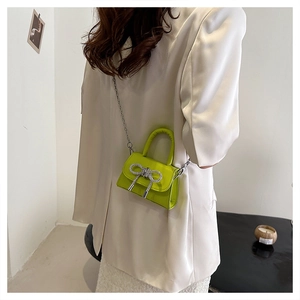 Détail d'un mini sac à main vert vif avec nœud en strass et bandoulière en chaîne argent