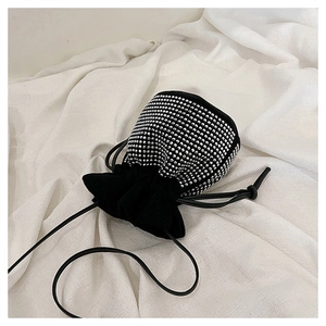 Macro detail of silver rhinestones and black suede drawstring on a bucket bag