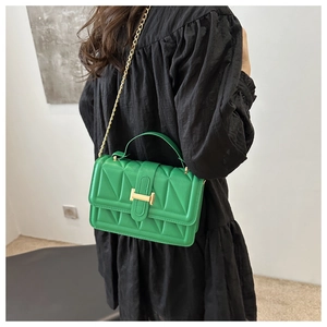 Close-up of green quilted leather bag with gold H-buckle and fine chain strap