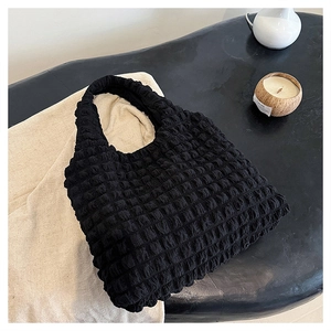 Macro shot of black popcorn textured fabric on a minimalist shoulder bag design