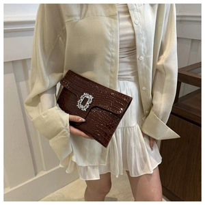 Detail of dark brown crocodile pattern PU leather clutch bag with a square rhinestone buckle