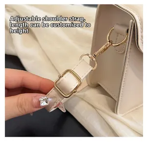 Detail showing the adjustable cream faux leather shoulder strap with gold metal buckle