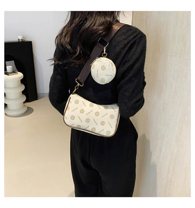 Detail view of stylish monogram crossbody bag with matching round mini coin purse on strap